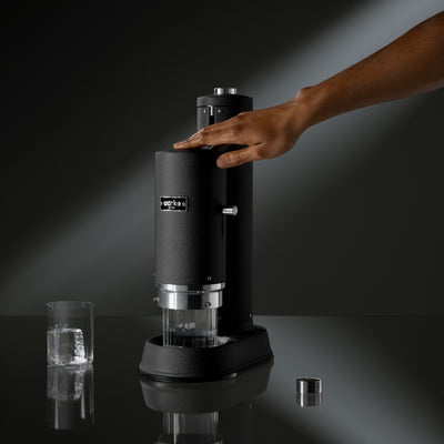 Hand pressing top of Aarke Carbonator Pro in Matte black to carbonate water.