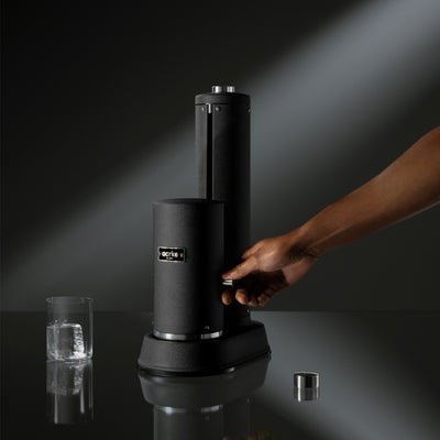 Person activating carbonation lever on Aarke Carbonator Pro to infuse water with CO2, modern and sleek design.