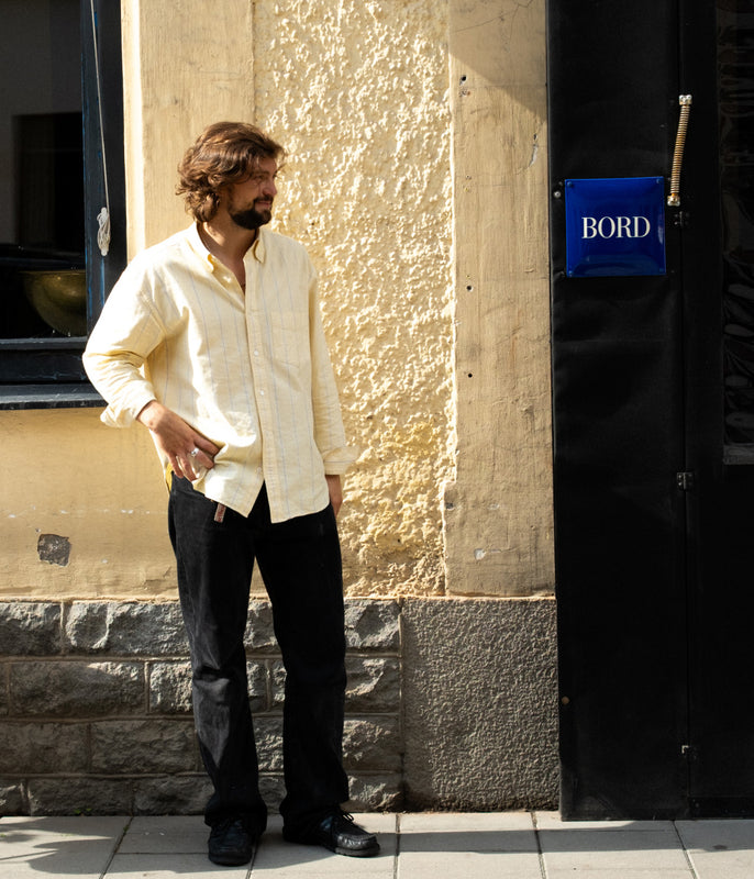 Man standing against a textured wall with a 'BORD' sign in the background