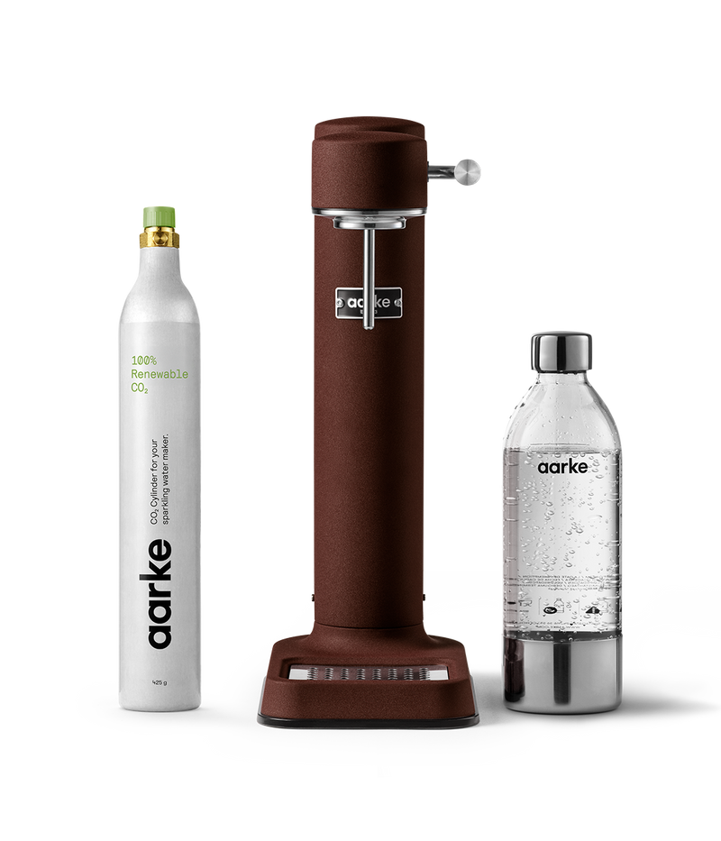 Aarke Carbonator 3 in Burgundy displayed with a 100% renewable CO2 cylinder and a PET water bottle.