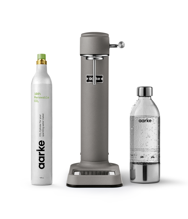 Aarke Carbonator 3 in Matte grey displayed with a 100% renewable CO₂ cylinder next to a filled PET water bottle.