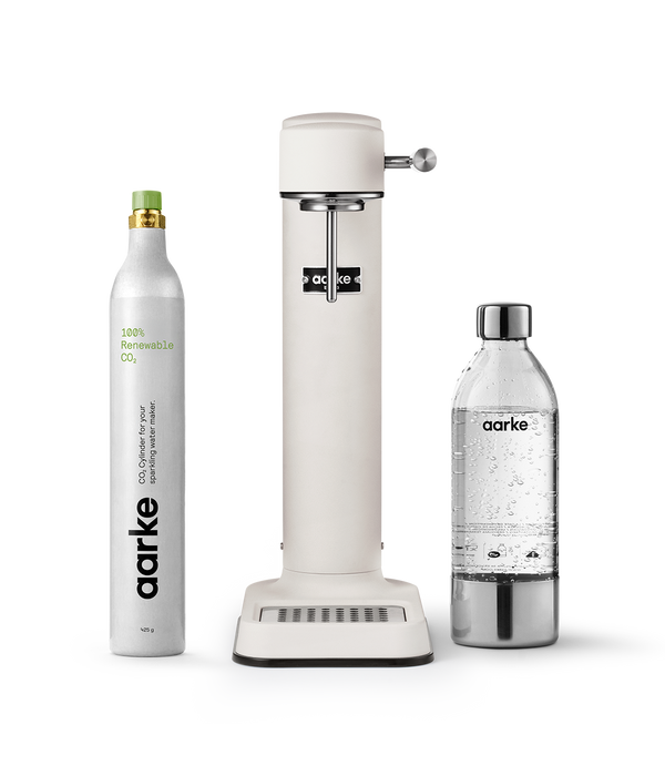 Aarke Carbonator 3 in Matte white displayed with a 100% renewable CO2 cylinder next to a filled PET water bottle.