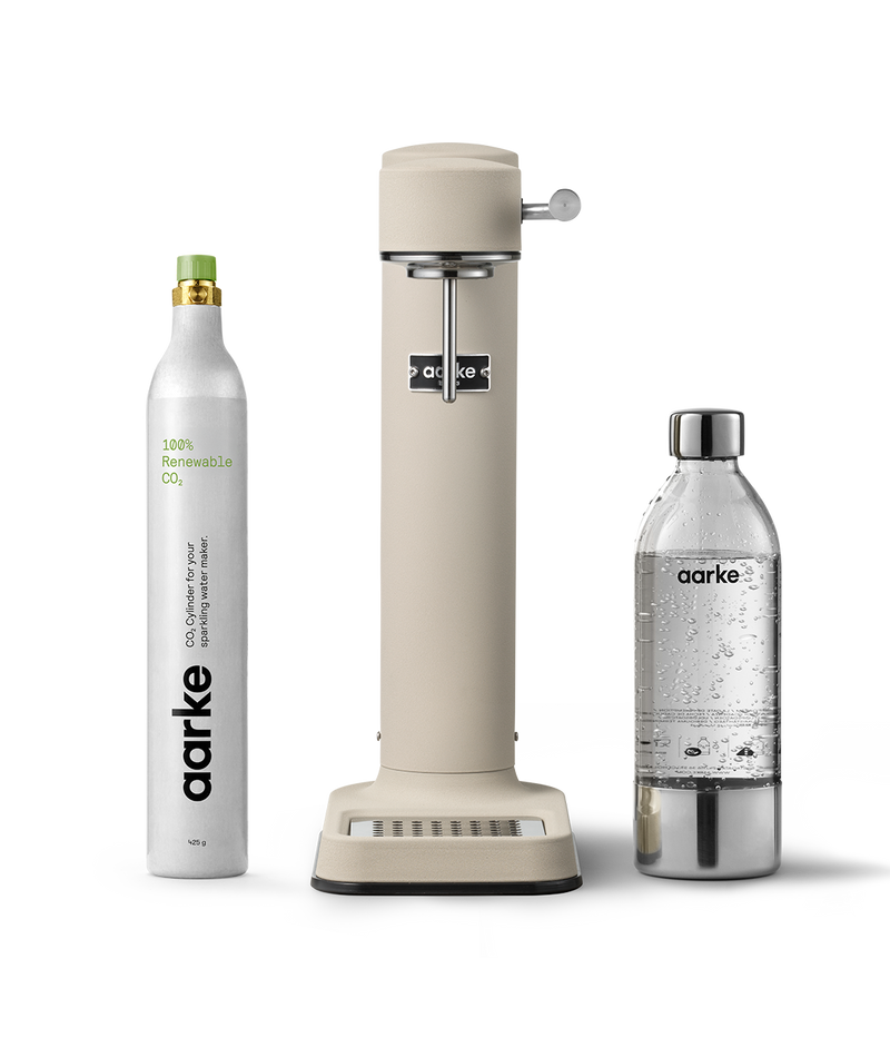 Aarke Carbonator 3 in Sand displayed with a 100% renewable CO2 cylinder next to a filled PET water bottle.