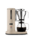 Aarke sand-colored automatic pour-over coffee maker with stainless steel filter brewing coffee into glass carafe.