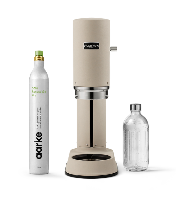Aarke Carbonator Pro in Sand with a 100% renewable CO2 cylinder and glass bottle filled with sparkling water.