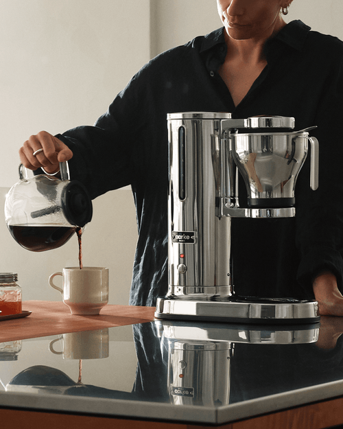 Aarke Coffee Maker in stainless steel with glass carafe, pouring freshly brewed filter coffee