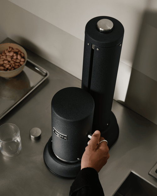Close-up of the Aarke Carbonator Pro in Matte Black, showing the carbonation lever being operated by hand.