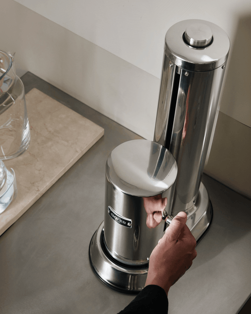 Close-up of the Aarke Carbonator Pro in Stainless Steel, showing the carbonation lever being operated by hand.