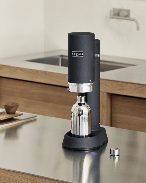 Aarke Carbonator Pro in Matte Black with a stainless steel To-Go Bottle Large, positioned inside the carbonator on a modern kitchen countertop.