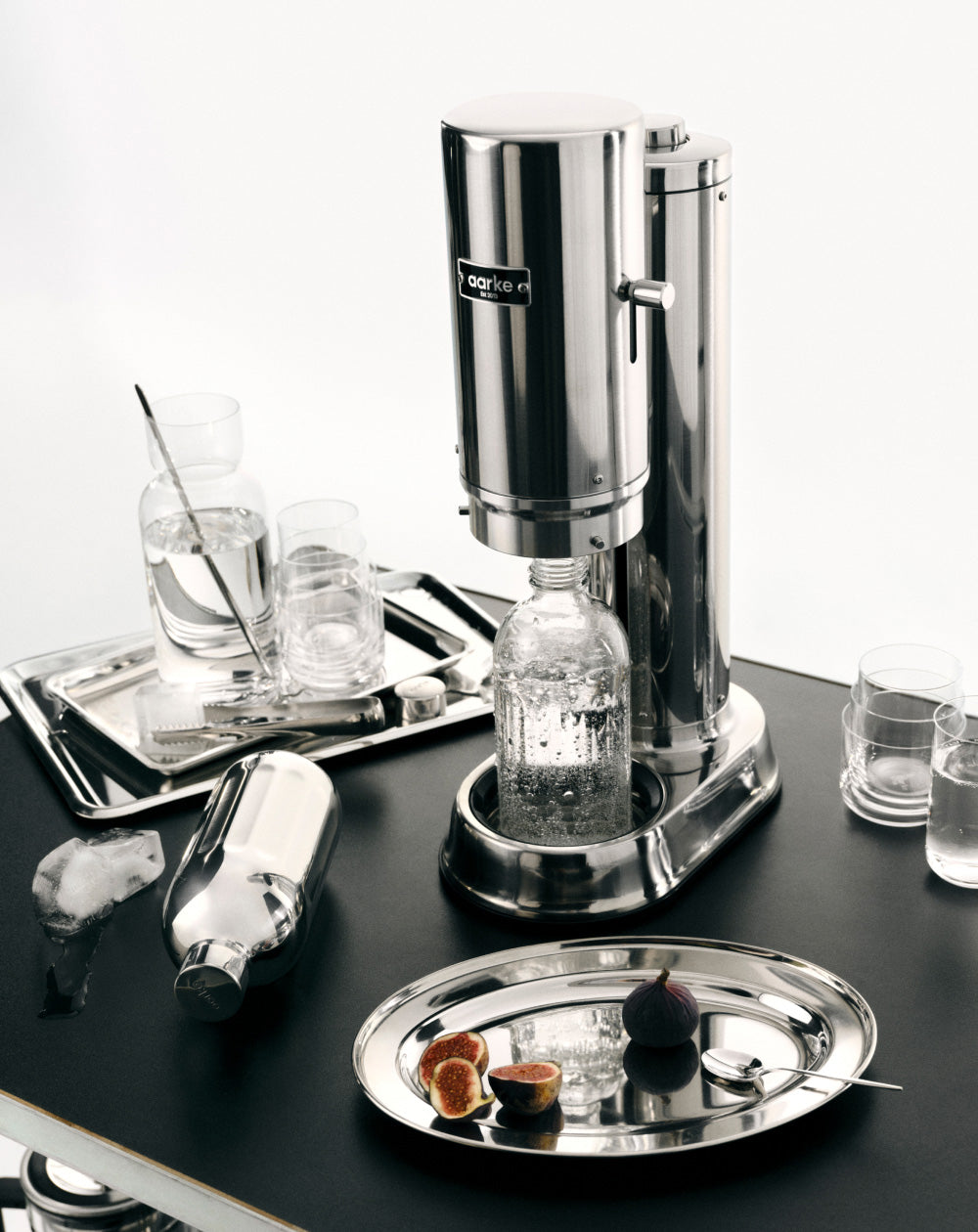 Carbonator Pro Stainless steel on a black tray with glasses and bottles.