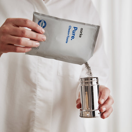 Pouring Aarke Pure filter granules into the stainless steel cartridge for water filtration.