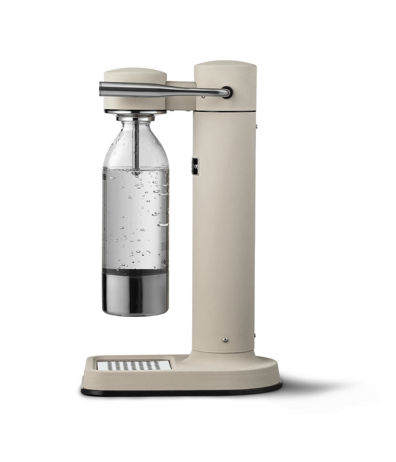 Side view of the Aarke Carbonator 3 in Sand with a carbonated PET water bottle attached, bubbles visible inside.