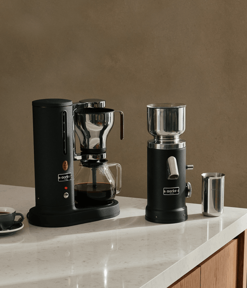 Aarke Coffee Maker and Coffee Grinder in Matte Black with stainless steel accessories on a kitchen countertop.