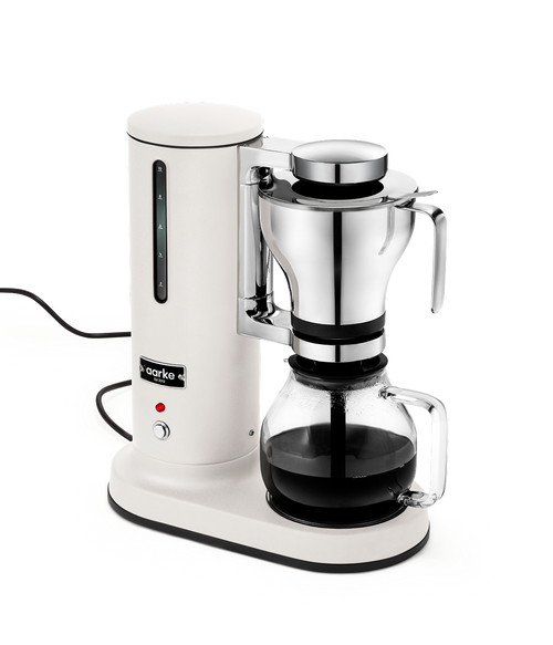 Aarke Coffee Maker in Matte White with a stainless steel brew basket and class carafe with freshly brewed coffee.